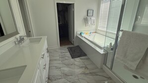 A modern bathroom with a large mirror, a bathtub, and a walk-in shower. - Desert Getaway Home 4 bed and 2 bath with luxurious upgrades (Palm Desert)