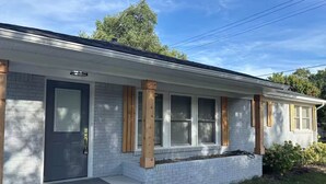 Una casa de un piso con fachada de ladrillo gris, una puerta principal y un pequeño porche.
