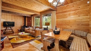A cozy cabin interior with a wooden dining table, bench seating, a sofa, and a fireplace. - Dorothy in the Woods | Fire Pit | Fireplace | Yard (Edgewater)