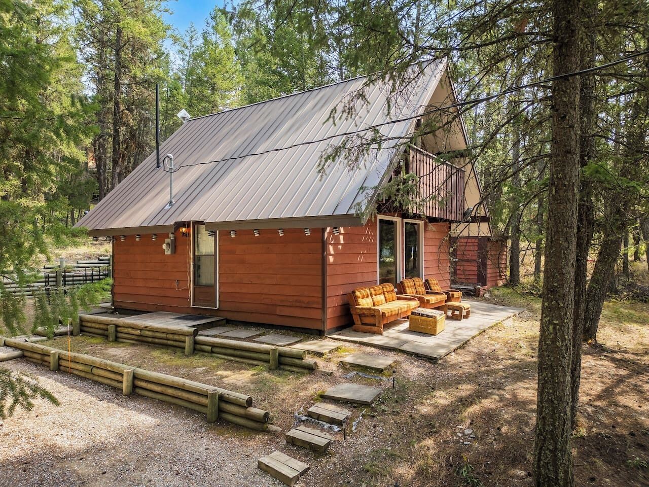 A cabin with a metal roof, wooden exterior, and a porch with seating.