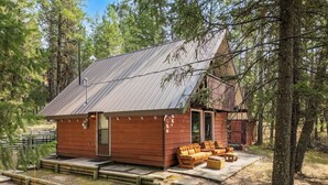 A cabin with a metal roof, wooden exterior, and a porch with seating. - Dorothy in the Woods | Fire Pit | Fireplace | Yard (Edgewater)