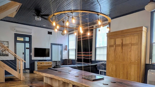 Une pièce spacieuse avec une longue table en bois, un ventilateur de plafond et un lustre moderne.