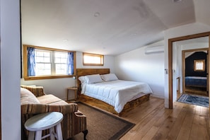 A bedroom with a wooden bed, a small seating area, and a window with curtains.