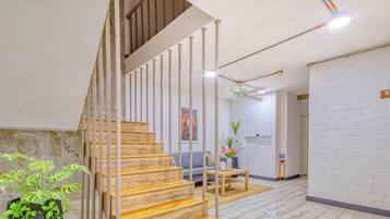 Eine Treppe mit Holzstufen und Metallgeländern, ein Deckenventilator, ein Sofa, ein kleiner Tisch und eine Pflanze.