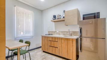 Una cocina compacta con refrigerador, microondas y estufa a gas.