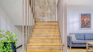 Un escalier avec des marches en bois menant à un mur de marbre, un canapé gris et une plante en pot.