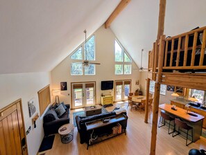 A spacious loft with a high ceiling, a dining area, a living room with a sofa and coffee table, and a kitchen with a bar.