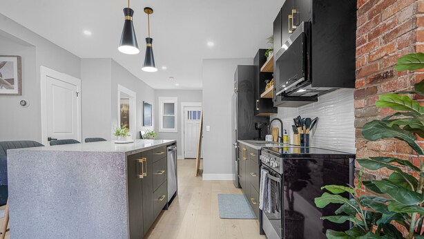 A modern kitchen with a central island, black cabinetry, and stainless steel appliances.