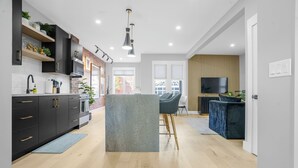 A modern kitchen with dark cabinetry, a central island, and a dining area with a blue sofa.