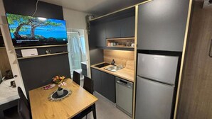 A compact kitchen with a built-in refrigerator, a sink, and a dining area with a table and chairs. - TJ Escape - Mobile Home With Hot Tub And Terrace (Pakoštane)