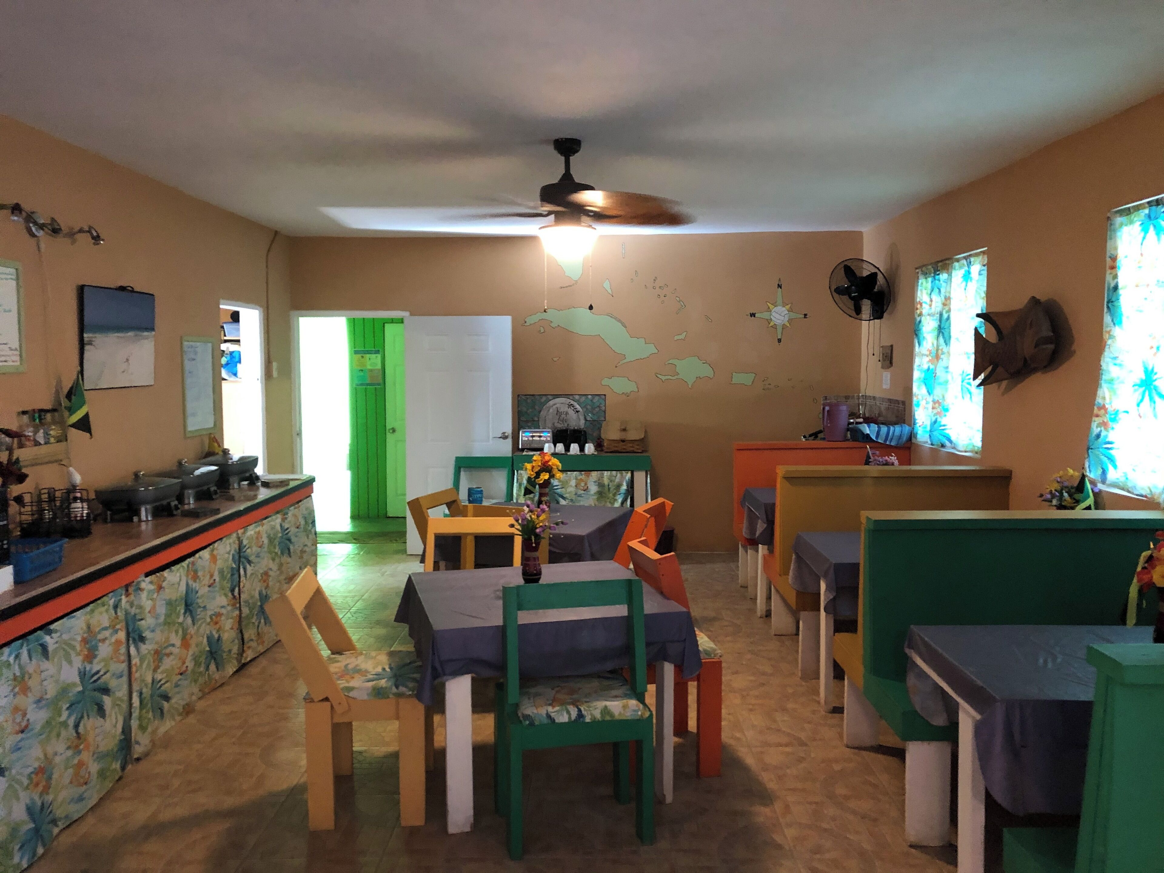 A room with a dining table, chairs, a bar area, and a green door.