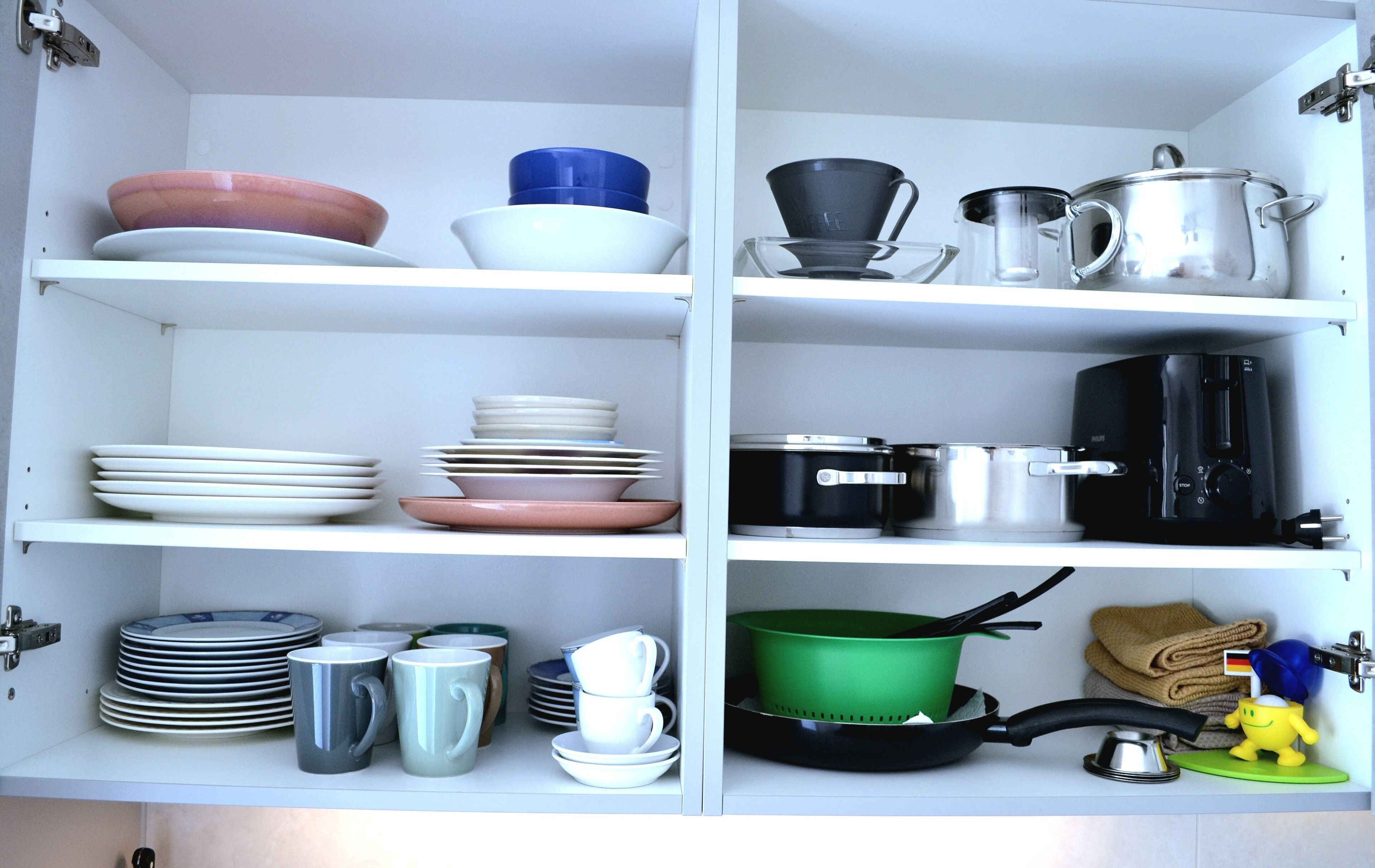 Una cocina con estantes que contienen diferentes platos, utensilios de cocina y una pequeña figurita.