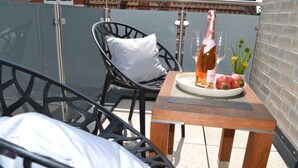 A balcony with a chair, a table, a bottle of wine, and a plate with apples. - KomfortPlus New Construction - Apartment with a sunny balcony and free parking (Bad Zwischenahn)