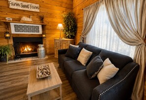 A cozy living room with a fireplace, a sofa, a coffee table, and a sign reading 'Farm Sweet Farm'.