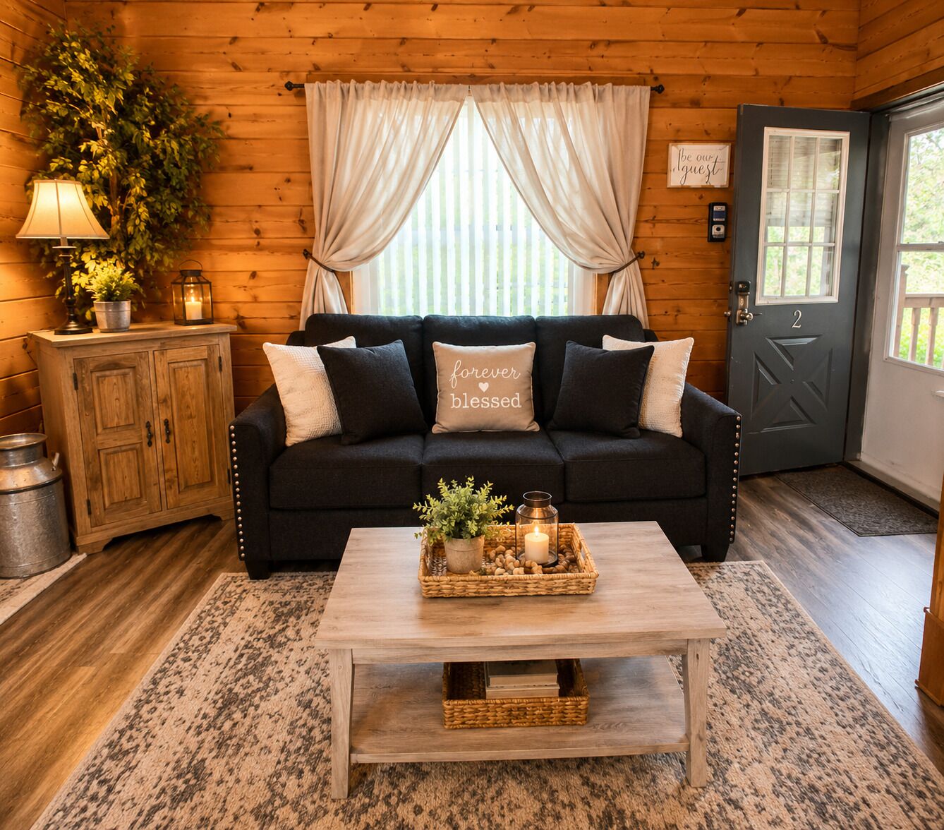 A cozy room with a dark-colored sofa, a wooden cabinet, a coffee table with a candle and a plant, and a door with a number.