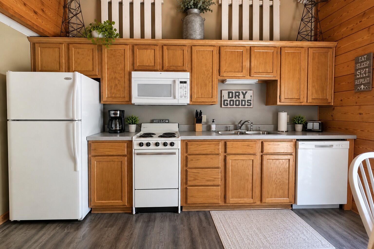 A kitchen with wooden cabinets, a white refrigerator, a microwave, a stove, and a sink.
