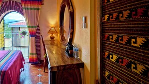 A room with a wooden table, a mirror, a lamp, and a patterned door. - Mountain view room (Oaxaca)