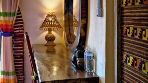 A room with a wooden table, a lamp, a mirror, and a colorful curtain. - Mountain view room (Oaxaca)