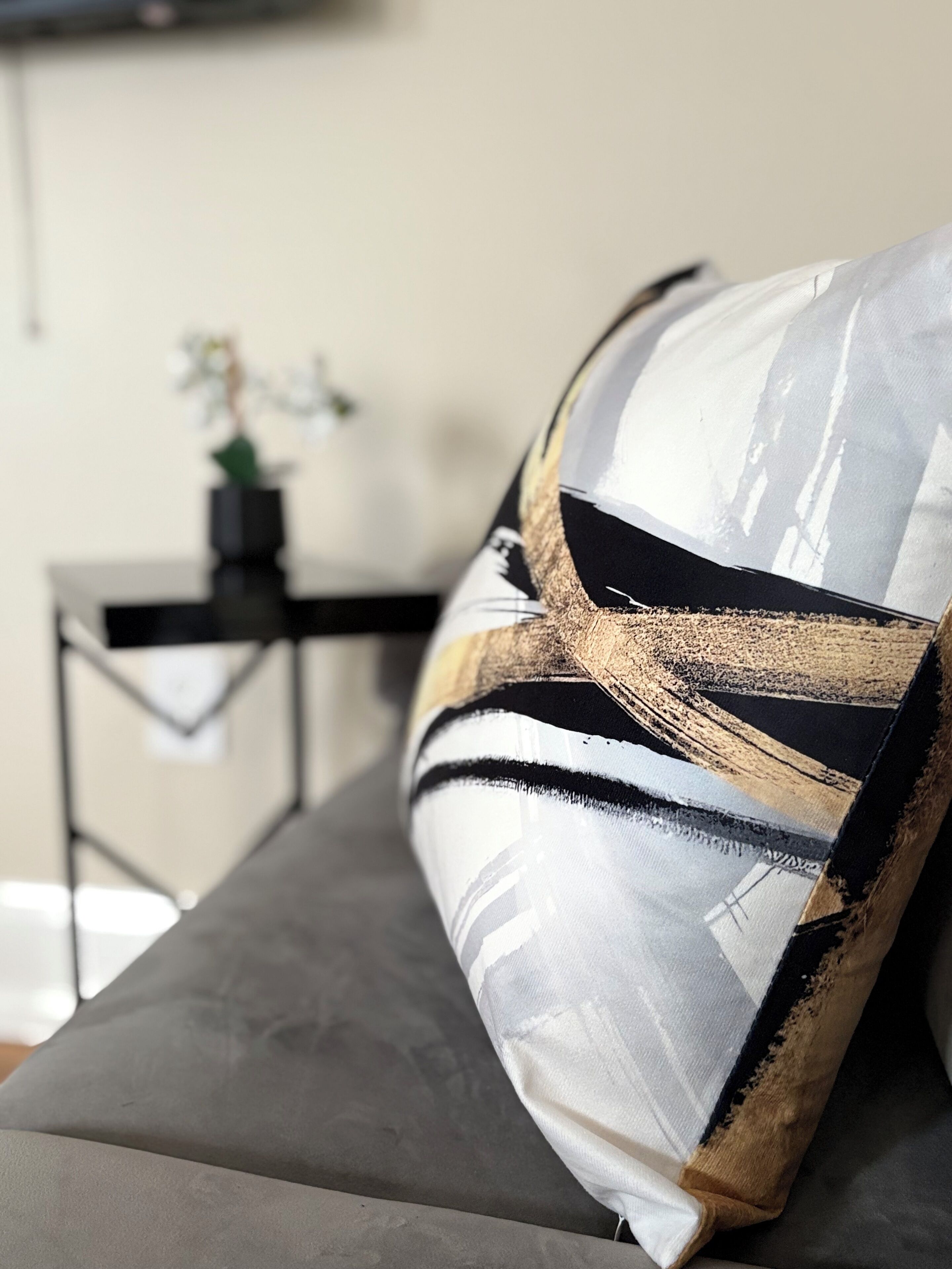A close-up of a pillow with a geometric pattern on a grey sofa.