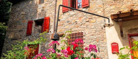 A stone building with red shutters and a bell.