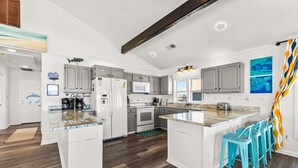 A modern kitchen with white cabinetry, a central island with bar stools, and a microwave.