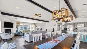 A spacious living room with a large wooden dining table, a sofa set, and a kitchen area with modern appliances.