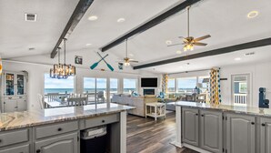 A spacious kitchen with a large island, dark wood flooring, and a view of the ocean.