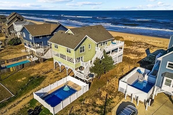 Une propriété située en bord de mer, comprenant plusieurs maisons, une piscine et offrant une vue sur la plage.