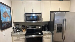 A kitchen with a stainless steel refrigerator, microwave, oven, and granite countertop. - Cozy home Gated community special deals (Kissimmee)