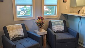 A cozy seating area with two armchairs, a small wooden table, and a vase of flowers.