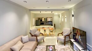 Una sala de estar moderna con sofá, sillas, una mesa de centro y televisor.