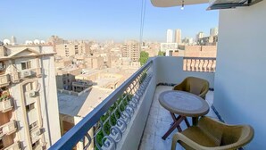 Un balcón con mesa y sillas, con vistas a un paisaje urbano de diversos edificios.