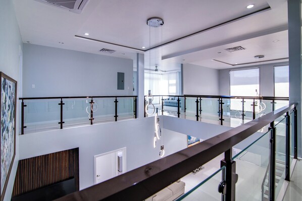 A spacious, modern hotel lobby with a high ceiling, glass railings, and a central island with a seating area.
