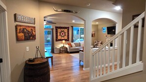 A spacious living room with a wooden floor, a sofa, a coffee table, and a TV mounted on the wall. - 2 min to Downtown Sisters, Family Friendly, XBOX, Game Rm, Outdoor Patio w/ BBQ, (Sisters)