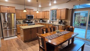 A modern kitchen with wooden cabinets, stainless steel appliances, and a dining area with a wooden table and chairs. - 2 min to Downtown Sisters, Family Friendly, XBOX, Game Rm, Outdoor Patio w/ BBQ, (Sisters)