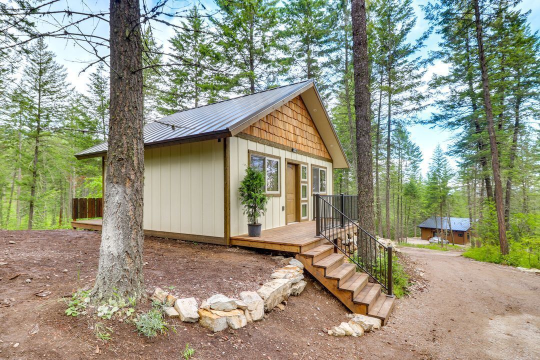 A cabin with a wooden exterior, a front porch, and a staircase leading to the entrance.