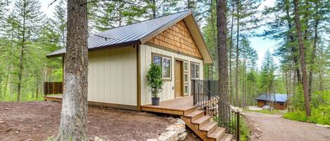 A cabin with a wooden exterior, a front porch, and a staircase leading to the entrance.