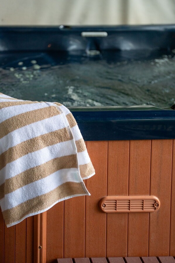 Una toalla sobre un panel de madera, un banco de madera y un jacuzzi con borde de madera.