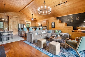 A log cabin interior with a dining area, living room, and kitchen.