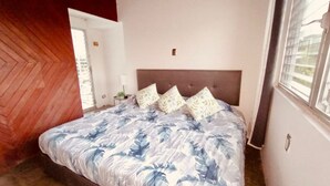 Una camera da letto con un letto grande, una testiera in legno e una finestra con persiane.