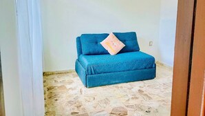 Un divano blu con un cuscino in una stanza con pavimento in pietra e un lampadario.