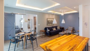 Una sala de estar moderna con una mesa de comedor de madera, un sofá azul y un sillón gris.