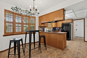 Una cocina con armarios de madera, un refrigerador negro, una isla integrada y un taburete de bar.