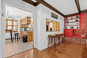 Una cocina con armarios de madera, una zona de bar con taburetes y una pared decorativa de ladrillo rojo.
