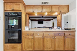 Una cocina con armarios de madera, un refrigerador negro y una encimera con un reloj y un letrero.