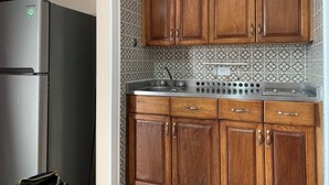 Una cocina con gabinetes de madera, un lavamanos de acero inoxidable y un refrigerador.