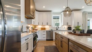 A modern kitchen with white cabinets, stainless steel appliances, and a large island. - Barefoot Dreams Waterfront w/Flat Lot, Pool, Paddleboards (Winchester)