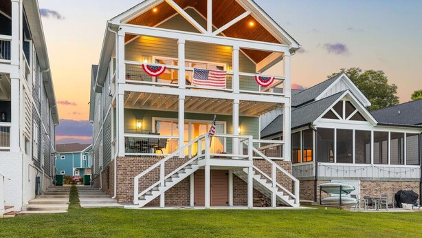 A multi-story building with a central staircase, a covered outdoor area with seating, and a view of the sunset. - Barefoot Dreams Waterfront w/Flat Lot, Pool, Paddleboards (Winchester)