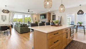 A spacious kitchen with a central island, pendant lighting, and a large window providing a view of the outdoors. - Barefoot Dreams Waterfront w/Flat Lot, Pool, Paddleboards (Winchester)