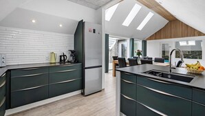 Een moderne keuken met een inbouwkookeiland, een koelkast en een eethoek met een tafel en stoelen.
